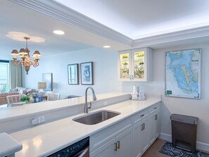 A modern kitchen with a built-in dishwasher, a stainless steel sink, and a large window.