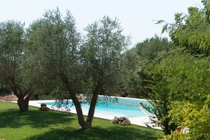 Una piscina rodeada de árboles y césped.