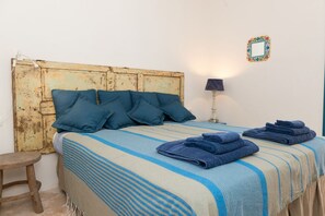 Una cama con ropa de cama azul, un cabecero de madera y una lámpara de noche.