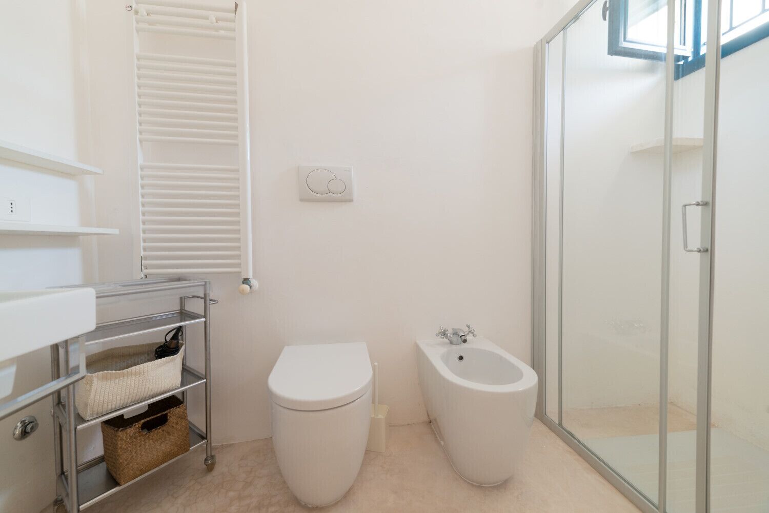 Een moderne badkamer met toilet, bidet en een douchecabine van glas.
