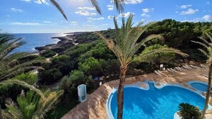 Un resort con piscina, palmeras y vista al mar.