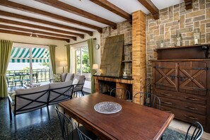 A cozy room with a wooden table, chairs, a sofa, and a stone fireplace.