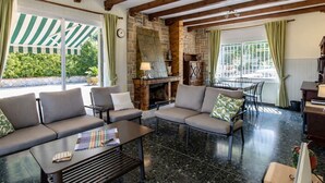 Un rincón tranquilo con sofás, una mesa de centro, una chimenea de piedra y ventanas amplias con cortinas.