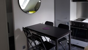 A compact kitchen with a dining area, including a foldable table and chairs, a round mirror, and a built-in oven. - St Lary-Vignec Nice little apartment ideally located (St Lary- Vignec)