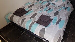 A neatly made bed with a geometric patterned bedspread and two folded towels on the bed. - St Lary-Vignec Nice little apartment ideally located (St Lary- Vignec)
