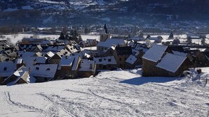 A snow-covered village with traditional houses and a church, surrounded by mountains. - St Lary-Vignec Nice little apartment ideally located (St Lary- Vignec)