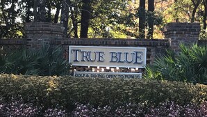 A sign for 'True Blue Golf & Dining' with a brick wall and greenery in the background. - Need to get away ... Cabin fever got you down. Take a trip to Pawleys Island, SC (Pawleys Island)