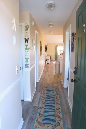 A hallway with a decorative rug, a door with a 'D' sign, and a wall with decorative letters.