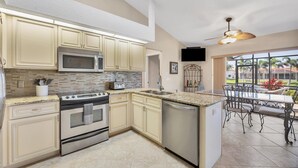 A modern kitchen with a large island, stainless steel appliances, and a dining area with outdoor seating. - Punta Gorda Isles 3 Bedroom Private Pool+Spa Home on Canal (Punta Gorde)