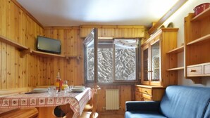A wooden cabin interior with a dining table, chairs, a sofa, and a television. - Des Alpes by Interhome (Canazei)