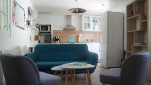 Una sala moderna con un sofá azul, dos sillones y una pequeña mesa blanca.