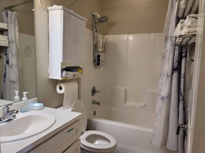 Een bad/douchecombinatie, een haardroger, handdoeken, zeep