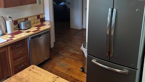Een keuken met houten kastjes, een roestvrijstalen koelkast, een vaatwasser en een betegelde spatwand.
