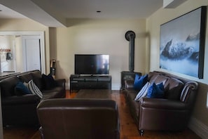 A living room with two leather sofas, a TV on a black stand, and a large painting on the wall.