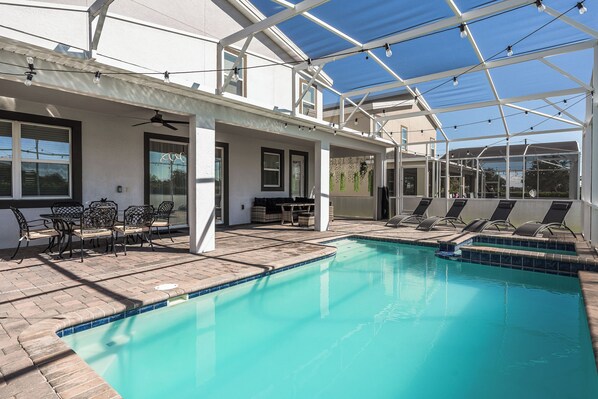 A pool area with lounge chairs and a covered patio.