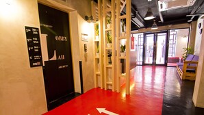 Een hotel lobby met een rode vloer, pijlen die de richting aangeven, een zwarte deur met 'LOBBY' erop, en een bord met kamer nummers.