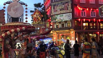 A street scene with a decorated bicycle, a building with illuminated signs, and a crowd of people.