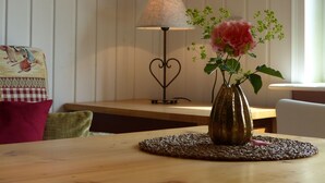 A wooden table with a vase of flowers, a lamp, and a checkered cushion. - VALUE HOF | cozy holiday house (Bracht)