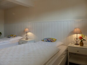Une chambre d’hôtel avec deux lits, du linge de lit blanc et des lampes de chevet.