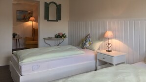 A bedroom with a bed, bedside table, lamp, and a small table with a plant. - VALUE HOF | cozy holiday house (Bracht)