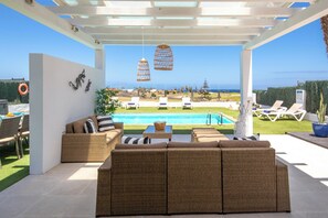 Un espace extérieur aménagé, abrité et doté de mobilier en osier, d’une piscine et d  ’une vue sur l’océan.