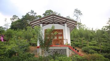 Situated amidst lush greenery, this charming building features a wooden porch and steps leading up to the entrance.