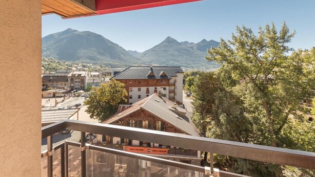 A hotel with a view of mountains, a parking area, and a Harley-Davidson sign.