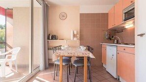 A compact kitchen with a dining table, chairs, and a small refrigerator.
