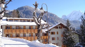 Ein schneebedecktes Gebäude mit hölzernen Balkonen, einer Straßenlaterne und einer Bergkulisse.