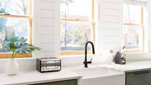A kitchen with a white countertop, green cabinets, a black faucet, and a window with blinds. - 100ft to King St. Outdoor Space, Modern Design! (Charleston)