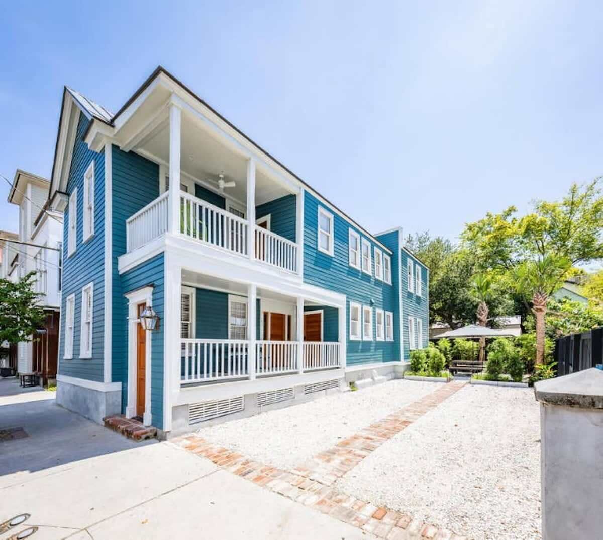 Ein blaues, zweistöckiges Haus mit Veranda und kleinem Garten.