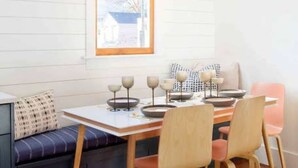 A dining area with a wooden table, four chairs, a bench, and a hanging light fixture. - 100ft to King St. Outdoor Space, Modern Design! (Charleston)