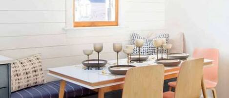A dining area with a wooden table, four chairs, a bench, and a hanging light fixture.