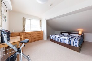 Une chambre à coucher avec un lit, un bureau sur lequel se trouve un vélo, une fenêtre et un climatiseur fixé au mur.