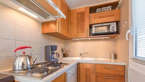 A compact kitchen with wooden cabinets, a stainless steel kettle, a coffee maker, a microwave, and a sink. - 150m from ski slopes, 4th floor, view mountain, balcony, tv, 31m², Serre Chevalier (Briançon)