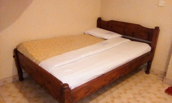 A small, single-bed room with a wooden headboard and a plain bedspread.