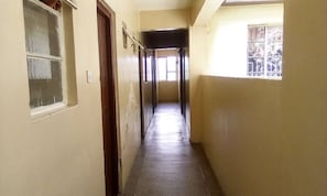 A narrow corridor with a wooden door on the left and a window on the right.