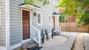 A two-story house with a front porch, a brick wall, and a wooden fence. - Gorgeous 6bd, 6ba Home, Made for Large Groups! (Charleston)