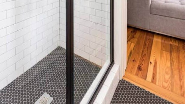 A modern bathroom with white subway tiles, a glass shower enclosure, and a wooden floor. - Gorgeous 6bd, 6ba Home, Made for Large Groups! (Charleston)