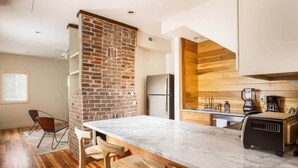 A kitchen with a brick accent wall, a marble countertop, and wooden cabinets. - Gorgeous 6bd, 6ba Home, Made for Large Groups! (Charleston)