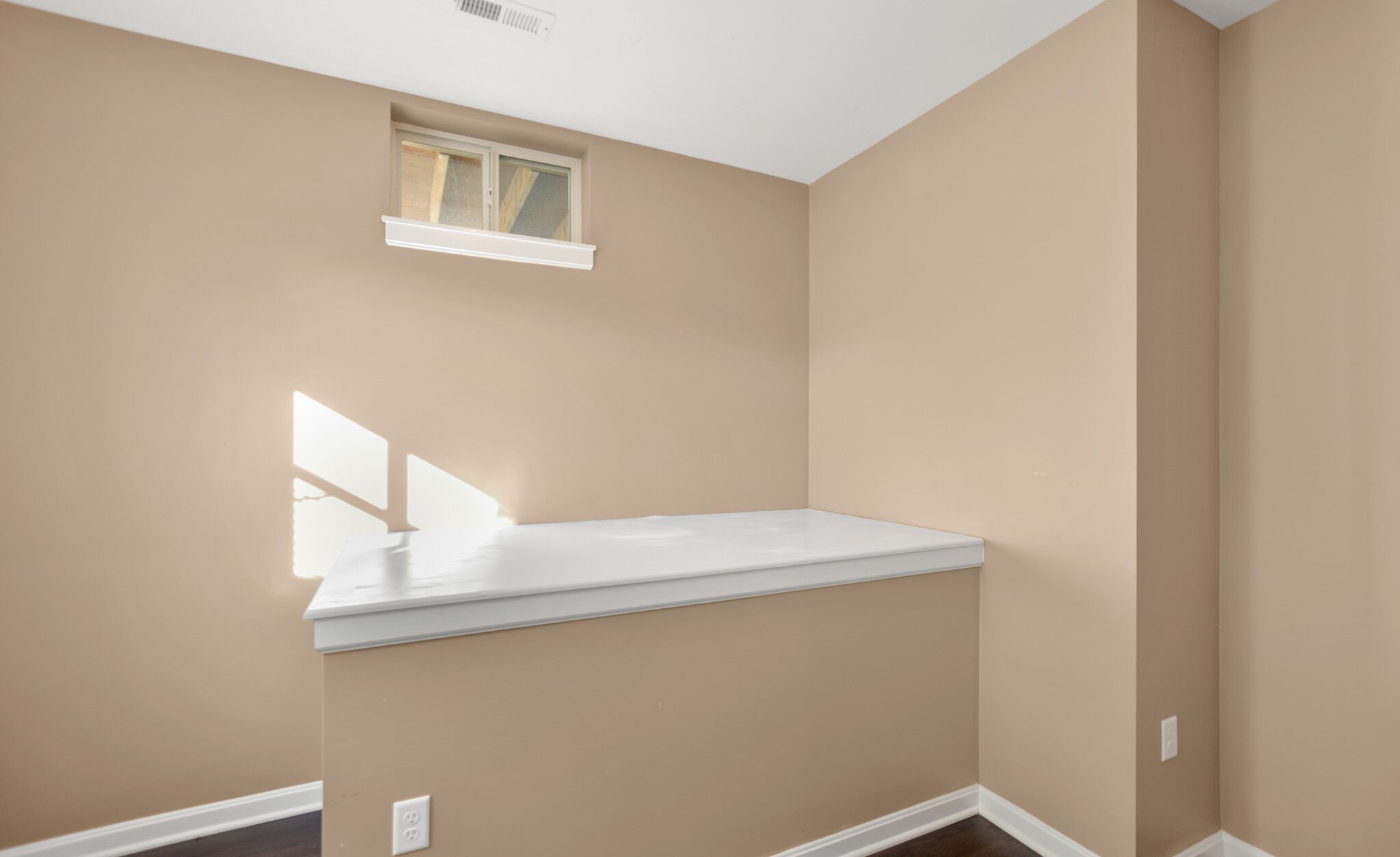 A room with a sloped ceiling, a window, and a built-in bench.