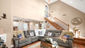 A spacious living room with a sectional sofa, a coffee table, and a staircase leading to an upper level. - Charming "Cream of the Crop" Cape ~❤️of Middletown (Middletown)