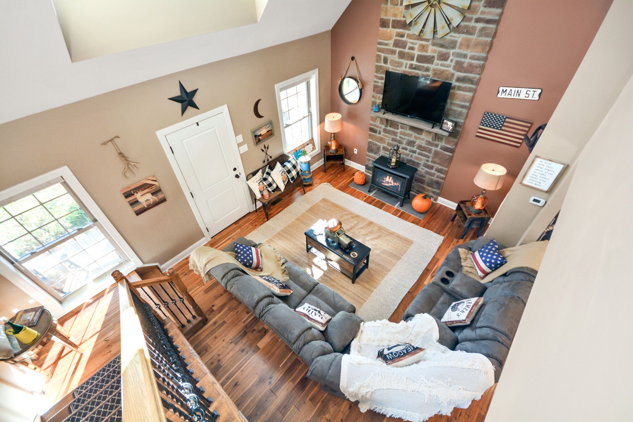 A spacious living room with a fireplace, a large sofa set, a television, and a staircase leading to an upper level.
