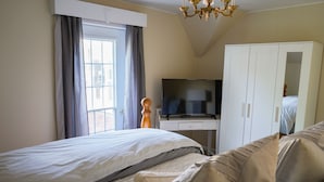 A bedroom with two beds, a television, a wardrobe, and a window with curtains. - Walk to Downtown or conservation area, 2 Bedroom home . Sleeps 4. Pets welcomed (Orangeville)