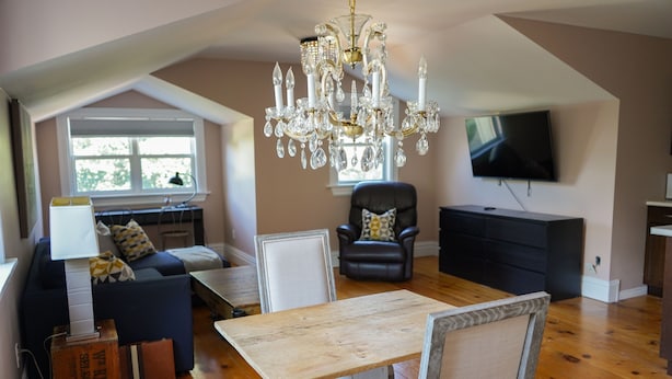 A spacious living room with a chandelier, a television, a dining table, and a sofa. - Walk to Downtown or conservation area, 2 Bedroom home . Sleeps 4. Pets welcomed (Orangeville)