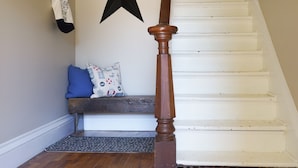 A staircase with a wooden handrail, a black star decoration, a bench with a blue cushion, and a clock on the wall. - Walk to Downtown or conservation area, 2 Bedroom home . Sleeps 4. Pets welcomed (Orangeville)