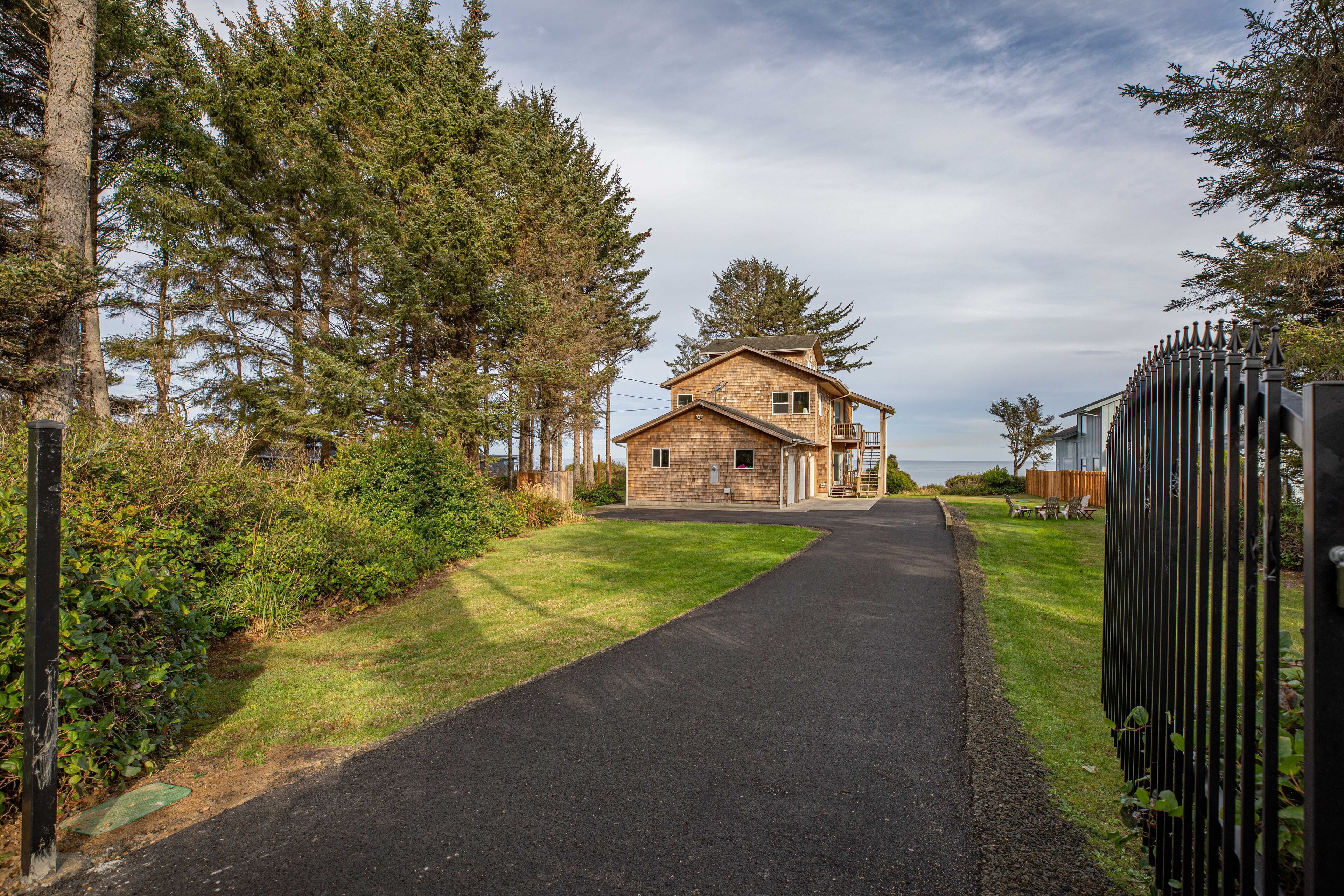 A two-story house with a paved driveway leading to a gated entrance.