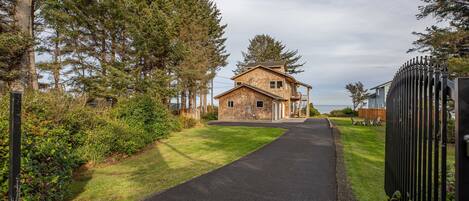 A two-story house with a paved driveway leading to a gated entrance.
