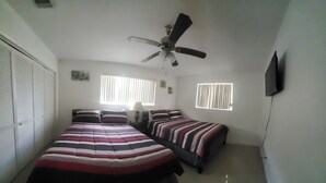 A bedroom with a large bed, two smaller beds, a ceiling fan, and two windows with blinds. - Jazzy Escapes (with pool) near Hard Rock Stadium (Miami)
