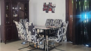 A dining area with a round table and chairs, a chandelier, a cabinet with decorative items, and a wall with framed pictures. - Jazzy Escapes (with pool) near Hard Rock Stadium (Miami)